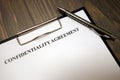 Clipboard with confidentiality agreement and pen on desk