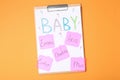 Clipboard with different baby names on orange background, top view Royalty Free Stock Photo