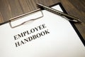 Clipboard with employee handbook and pen on desk