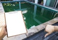 Clipboard in girl hand over green pool, Dirty pool water in tropical summer Royalty Free Stock Photo