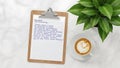Clipboard with handwritten notes and latte art coffee on marble surface image photo Royalty Free Stock Photo