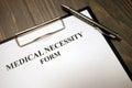 Clipboard with medical necessity form and pen on desk Royalty Free Stock Photo