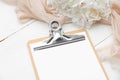 Clipboard mockup and peony flowers on white wooden table with beige cloth. Flat lay, top view. Wedding checklist, planner, to do Royalty Free Stock Photo