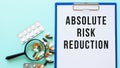 A clipboard with paper lies on a table near drugs. Inscription ABSOLUTE RISK REDUCTION.