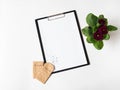 Clipboard and paper for text, burgundy primrose flower and seeds in paper bags on white background. Garden concept. Top view Royalty Free Stock Photo