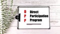 Clipboard with text direct participation program and pen on white wooden background with green plant Royalty Free Stock Photo
