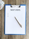 Clipboard with text next step on wood desk. Royalty Free Stock Photo