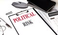 Clipboard with text political risk on desk with charts, calculator, notebook and pen Royalty Free Stock Photo