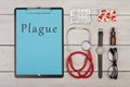 clipboard with text & x22;Plague& x22;, pills, stethoscope, eyeglasses and watch on white wooden background