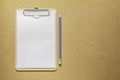 Clipboard with white paper and pencil on wooden table.