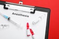 Clipboard with word Anesthesia, syringe and ampules on red background, top view