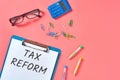 Clipboard with words tax reform near stationery items on pink desk Royalty Free Stock Photo