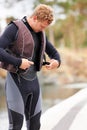 Clipping on his lifevest. Smiling young guy clipping on his life-vest at the lake.