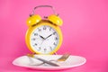 Clock with alarm and empty plate with knife and fork. Chrono diet concept