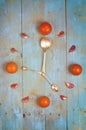 Clock arranged from tomatoes, garlic and spoons. Textured abstract clock face showing 5. Blue background