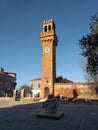 a clock with a beautiful and elegant red brick bell tower next to the outdoor terrace