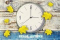 Clock and beautiful yellow autumn leaves on a wooden background. Inscription, Hello Autumn. Royalty Free Stock Photo