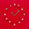 Clock built with wooden balls as hours and leaves as hands on a red background