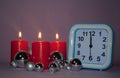 Clock and Christmas silver balls with red candles. Blurred lights in the background. New Year Royalty Free Stock Photo