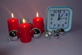 Clock and Christmas silver balls with red candles. Blurred lights in the background. New Year Royalty Free Stock Photo
