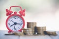 Clock with coin on table. Time investment or retirement saving. Save money for future use. Business and finance concepts