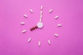 Clock created from white pills and brown tablets on pink background. Right time for using medicines