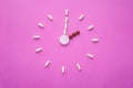 Clock created from white pills and brown tablets on pink background. Right time for using medicines