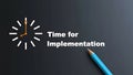 Clock face indicating 9:00 with text \'Time for Implementation\' and a blue pencil on a dark Royalty Free Stock Photo