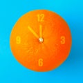 A clock in the form of an orange on a blue pastel background. Minimalism. The concept of summer, time. Royalty Free Stock Photo