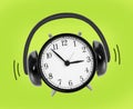 Clock with headphones around made from clock bells on green background Royalty Free Stock Photo