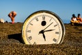 A clock is laying on the sand with the hands at 3:00 Royalty Free Stock Photo