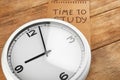 Clock and paper sheet with inscription TIME TO STUDY on wooden background. Time management concept Royalty Free Stock Photo