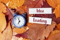 Clock is on a pile of leaves with the words idea loading written on a piece Royalty Free Stock Photo