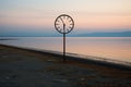 a clock on a pole at the edge of a body of water