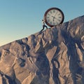 Clock push. Man pushes a clock on a rocky cliff