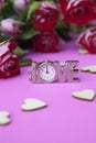 A clock in the shape of a word of love. On a pink background, hearts and flowers of roses. The concept of valentines day, wedding Royalty Free Stock Photo