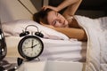 Clock show 2 O`clock and woman sleepless on bed