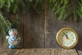 Clock and snowman under the Christmas tree on a wooden background Royalty Free Stock Photo