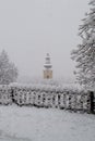 Clock and spire of a church bell tower under snowfall Royalty Free Stock Photo