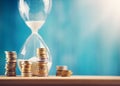 Clock with stacked coins and hourglass on blue background Royalty Free Stock Photo