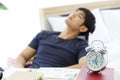 Clock on Table in front of Tired Asian man napping at a office after a hard workday.