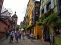 Clock tower and traditional Houses with colorful facades and sloping roofs in Riquewihr, France.