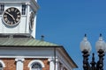 A clock in a turret on the roof of a brick building.