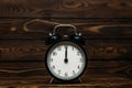 Clock on a wooden background. The clock shows the time of twelve o`clock in the afternoon. Clock showing the time of twelve o` Royalty Free Stock Photo