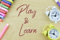 Clocks, pen colors and clothespins with text PLAY and LEARN