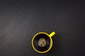 Clockwise stir. Yellow cup of black coffee flat lay on scrathed rough black background. Copy space for your text, image, message.