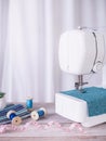 Sewing machine working with blue fabric, sewing accessories on the table, stitch new clothing Royalty Free Stock Photo