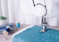Close-up sewing machine working with blue fabric, sewing accessories on the table, stitch new clothing Royalty Free Stock Photo
