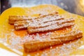 Cloes up Churros topping with icing sugar served with nutella sauce on yellow plate