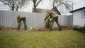 Cloned caucasian men work together in the garden, cloudy, summer day